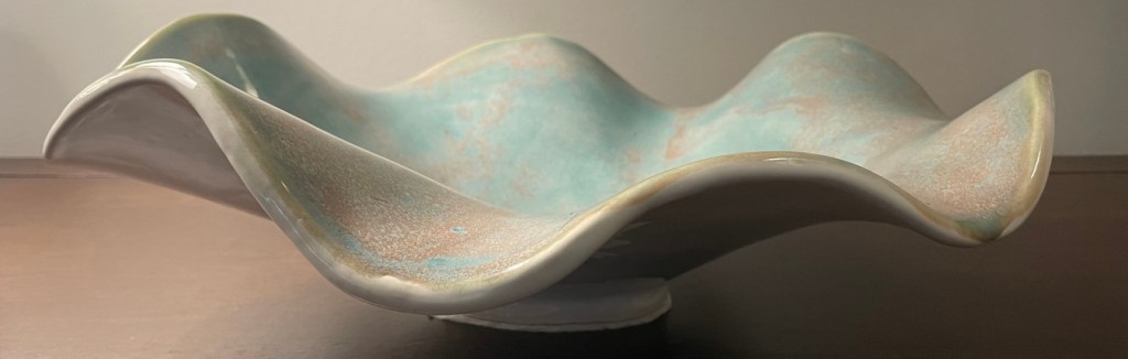 Handmade pottery bowl with wavy scalloped edge design.